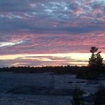 Sunset over water with small islands and pine trees