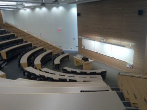 Photo taken at the back of a 200-seat lecture hall looking toward the front white board.