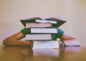 Student behind a pile of text books.